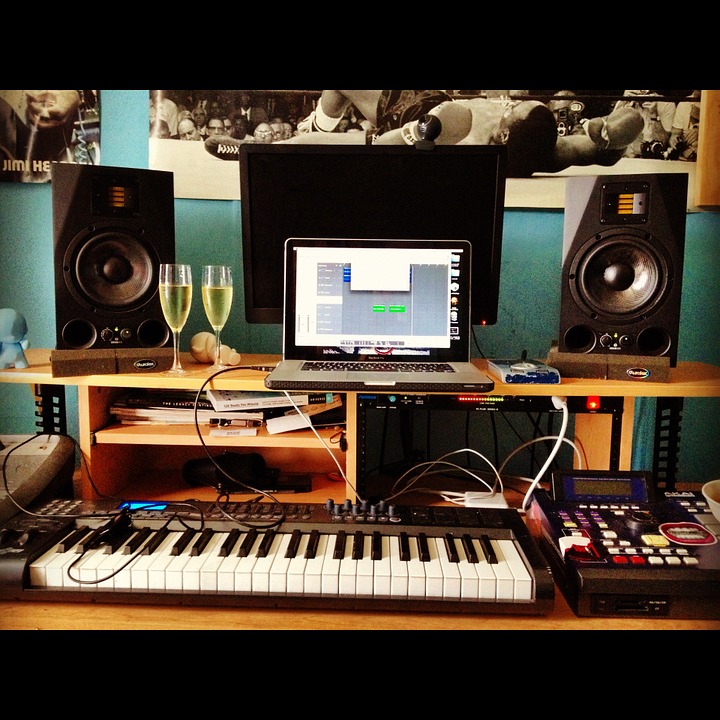 Centro de produção musical com piano, teclado e laptop.